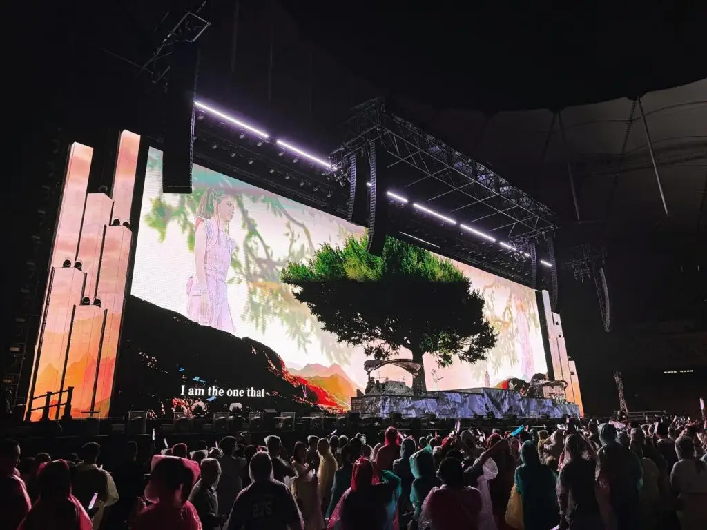 Concert stage featuring a large LED screen displaying a scenic image with a tree and mountains.